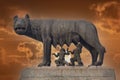 She wolf roman empire symbol breast feeding newborn romolus and remus statue on red sunset background Royalty Free Stock Photo