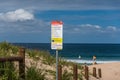 Warning sign on Wollongong city beach with sand dunes on the background Royalty Free Stock Photo