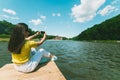 Womam sitting on a lake pier and taking picture Royalty Free Stock Photo