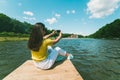 Womam sitting on a lake pier and taking picture Royalty Free Stock Photo