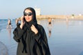Woman in abaya using phone on the beach Royalty Free Stock Photo
