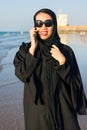 Woman in abaya using phone on the beach Royalty Free Stock Photo