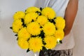 Woman with abouquet of yellow chrysanthemums. Beautiful fresh yellow flowers for holiday. Woman holding beautiful yellow flowers