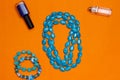 Woman accessories turquoise necklace, bracelet and parfume on orange background