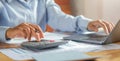 Woman accountant use calculator and computer with holding pen on desk in office. finance and accounting concept