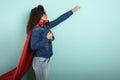 Woman acts like a superhero. Concept of determination and power. Cyan background Royalty Free Stock Photo