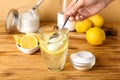 Woman adding baking soda into glass with water on wooden table Royalty Free Stock Photo