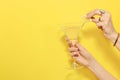 Woman adding lemon slice to martini glass of refreshing cocktail on yellow background, closeup. Space for text