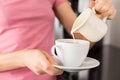 Woman adding milk to her coffee