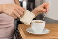 Woman adding milk to her coffee