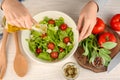 Woman adding olive oil into bowl with fresh vegetable salad on table Royalty Free Stock Photo