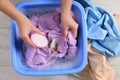 Woman adding powdered detergent into basin with clothes, top view. Hand washing laundry