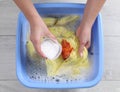 Woman adding powdered detergent into basin with clothes, top view. Hand washing laundry