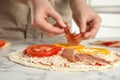 Woman adding prosciutto to pizza marble table, closeup Royalty Free Stock Photo