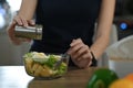 Woman adding salt in healthy vegetable salad glass bowl. Healthy lifestyle.