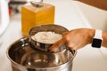 Woman adding salt to flour. Woman doing homemade pizza. Dressed in white pinny