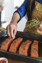 Woman adding spices and herb to raw salmon