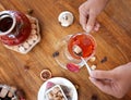 Woman adding sugar to a red berry tea. Top view of buttered cookies and tea kettle. Sweet breakfast. Cosiness concept. Royalty Free Stock Photo