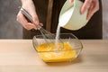Woman adding sugar to whisked eggs at wooden table, closeup Royalty Free Stock Photo