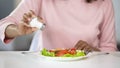 Woman adding too much salt to her food, unhealthy eating, dehydration problems Royalty Free Stock Photo