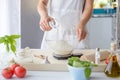 Woman adding water to flour in a bowl.