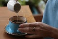 Woman adding water to fresh aromatic coffee at table