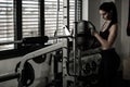 Woman adding weight on a bar as she workout in fitness gym