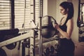 Woman adding weight on a bar as she workout in fitness gym