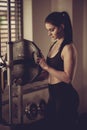 Woman adding weight on a bar as she workout in fitness gym