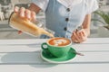 Woman adds brown cane sugar from a bottle to her cappuccino cup at a coffee shop. The concept of fast carbohydrates and