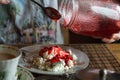 Woman adds jam to cottage cheese. Tea with milk. Jar of jam.