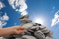 Woman adds rock to cairn under sun filled sky Royalty Free Stock Photo