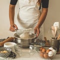 Woman adds some flour to dough on wooden table. Woman hands kneading fresh dough. Royalty Free Stock Photo