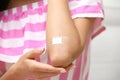 Woman with adhesive bandage on elbow against light background Royalty Free Stock Photo