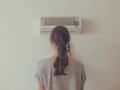 Woman Adjusting Air Conditioner at Home