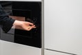 Woman adjusting microwave ovens settings using knob