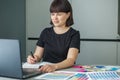 Woman administrative manager taking notes on information viewed on laptop. Office worker smiling