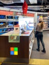 Woman admiring Multiple Microsoft Surface tablets and notebooks for sale at dedicated Microsoft stand inside FNAC French