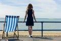 Woman admiring the sea from promenade with a deck chair Royalty Free Stock Photo