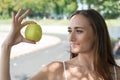 Woman adorable and healthy holds green apple. Secret of her beauty is healthy nutrition. Girl dieting or support