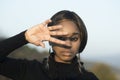 Woman with african appearance against sunlight, light background, defocused. Girl on calm relaxed face hiding out of