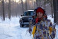 The woman against the background of the winter forest and the car with a mug of hot tonic. Picnic in the fresh air