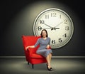 Woman against big white clock in dark room Royalty Free Stock Photo