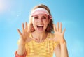 Woman against blue sky shouting through megaphone shaped hands Royalty Free Stock Photo