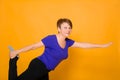 Woman at the age of doing yoga standing on a yellow background Royalty Free Stock Photo