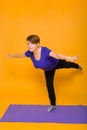 Woman at the age of doing yoga standing on a yellow background Royalty Free Stock Photo