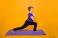 Woman at the age of doing yoga standing on a yellow background Royalty Free Stock Photo