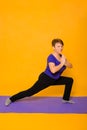 Woman at the age of doing yoga standing on a yellow background Royalty Free Stock Photo