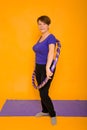 The woman at the age holds in hands a hoop for gymnastics standing on a rug. Studio photo on a yellow background Royalty Free Stock Photo