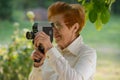 Woman ages shoots a movie camera park.